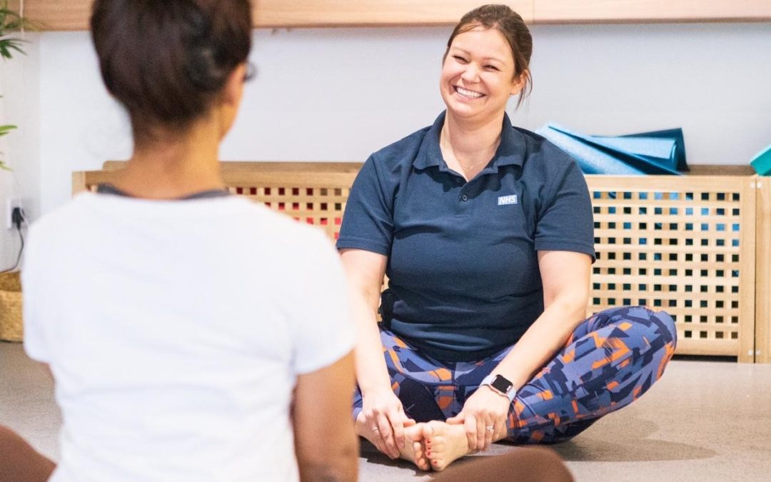 Hayley sits cross-legged on the floor, smiling at her class attendees